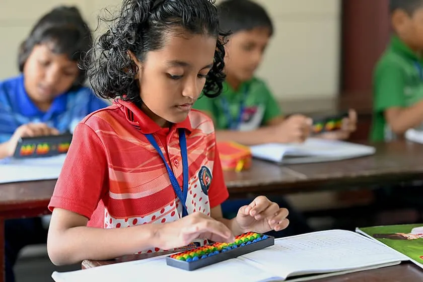 A girl working an abacus at her desk during class