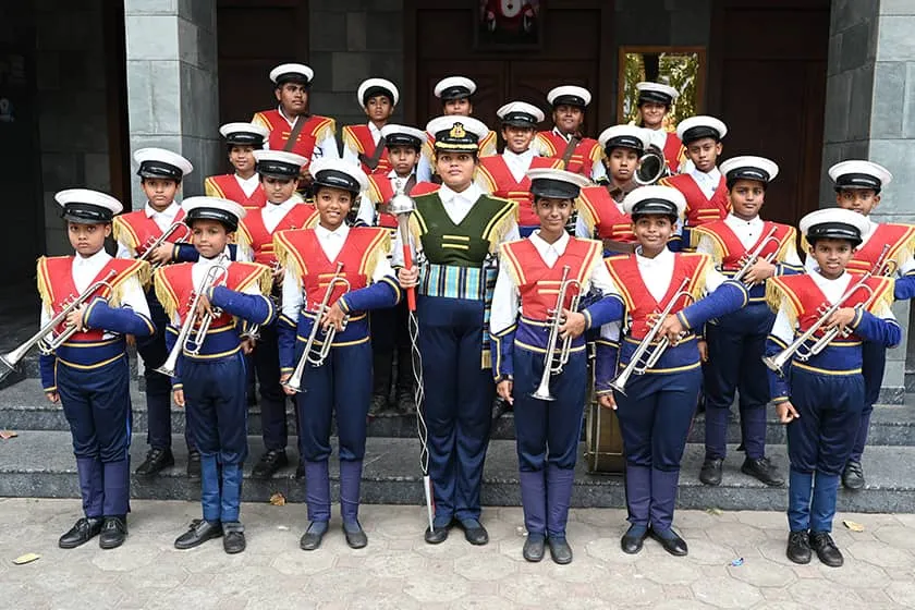 The Don Bosco school band in red and white uniforms with brass instruments and drums