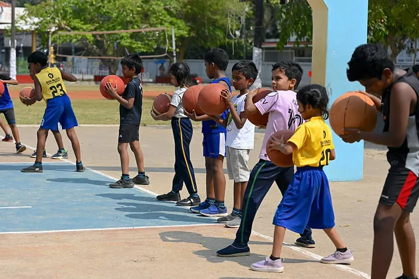 Children practising basketball drills on the outdoor court