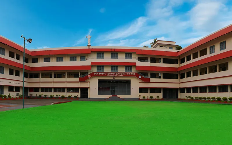 The Don Bosco Senior Secondary School building in Vaduthala behind a wide green lawn
