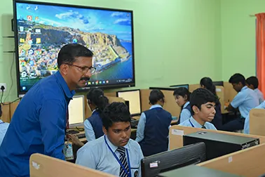 A teacher helping students at the computer lab
