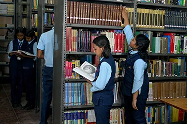 Students choosing books from the shelves of the school library