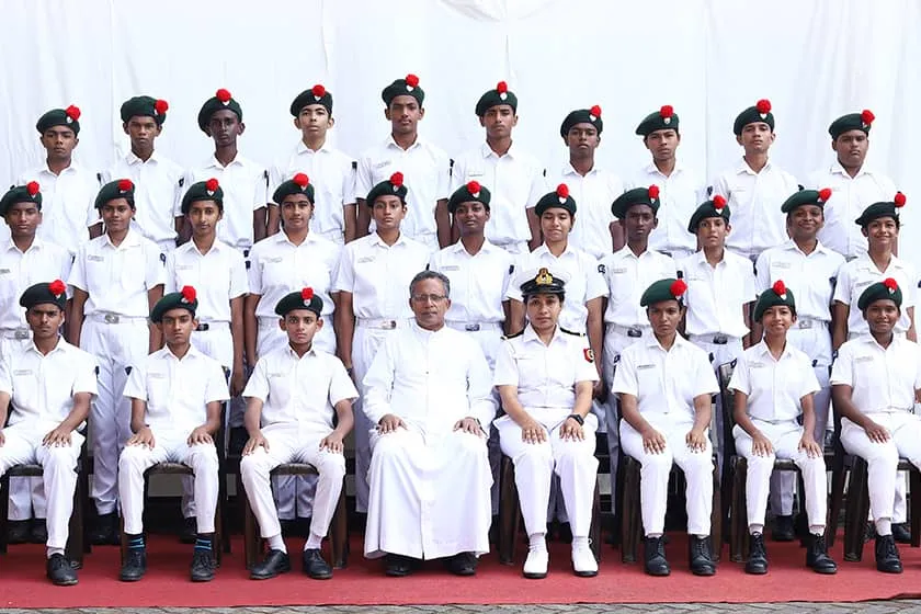 Naval NCC cadets in white uniforms seated with school staff for a group photo