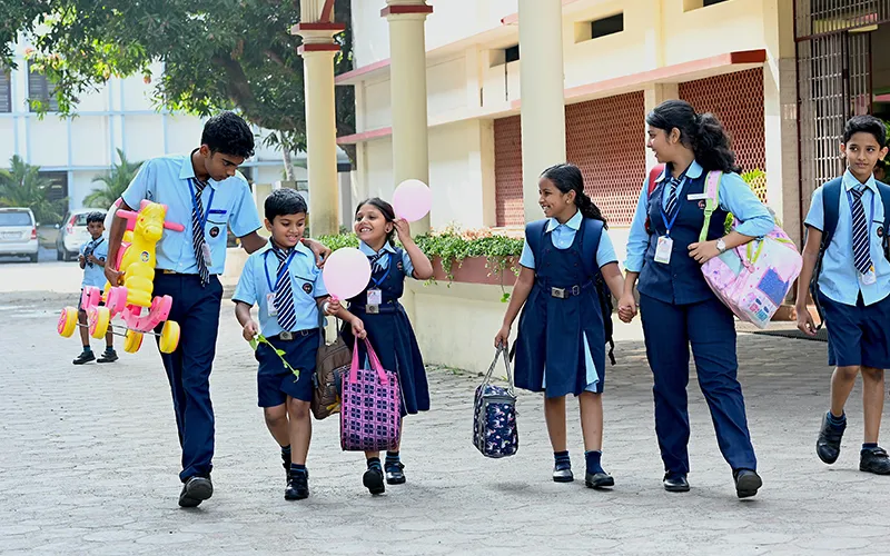 Students in Don Bosco uniforms walking across the school courtyard with their bags